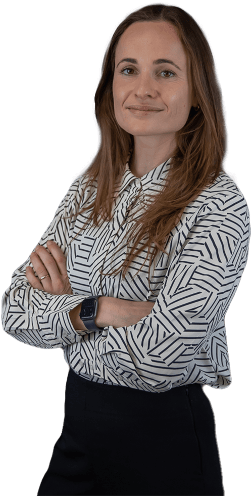 Persoon in blouse met patroon lacht vriendelijk naar je met de armen over elkaar heen.